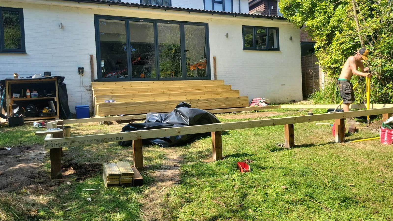 Timber deck frame under construction against the rear of a house